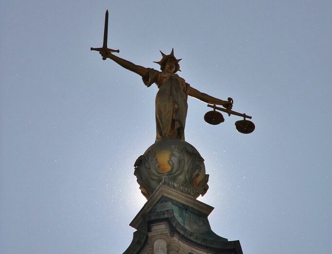 Image of the statue of justice holding a sword and scales on top of the Old Bailey courtrooms in central London.